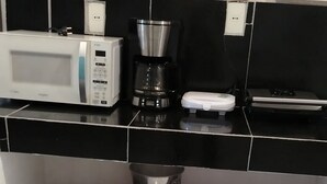 A kitchen with a microwave, coffee maker, and various dishes and utensils on shelves. - Hostal Deluxe Py offers you comfort, friendliness and (Asunción)