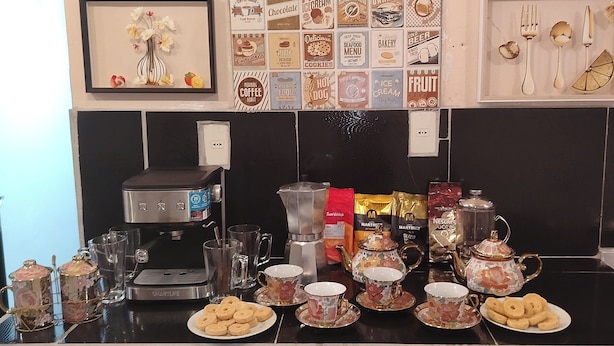 A kitchen counter with a coffee maker, teapot, cups, and cookies. - Hostal Deluxe Py offers you comfort, friendliness and (Asunción)