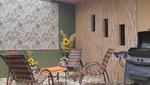 A patio with wicker chairs, a barbecue grill, and sunflowers. - Hostal Deluxe Py offers you comfort, friendliness and (Asunción)
