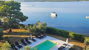 A pool area with lounge chairs and a view of a calm lake with boats. - Nice apartment in Pirovac (Pirovac)