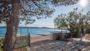 A stone pathway leading to a beach with a view of the sea and distant hills. - Nice apartment in Pirovac (Pirovac)