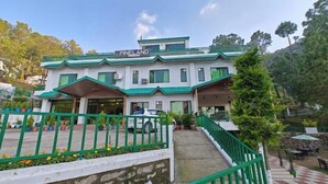 A building labeled "PineLand" with a green roof, a covered entrance, and a car parked in front. - Pineland Chalets And Resort (Kasauli)