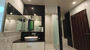 A modern bathroom with a marble vanity, a large mirror, and a dark wooden door. - Pineland Chalets And Resort (Kasauli)