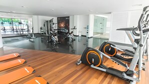 A modern gym with cardio equipment, weight machines, and a large mirror. - Modern and Spacious Family Loft with Private Beach / Relax in Cartagena (Cartagena de Indias)
