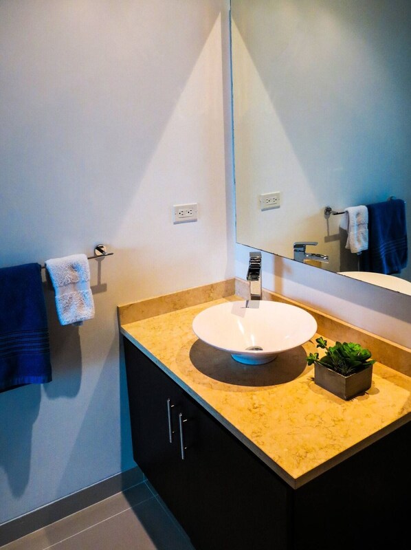 A modern bathroom with a white sink, dark cabinets, and a large mirror. - Modern and Spacious Family Loft with Private Beach / Relax in Cartagena (Cartagena de Indias)