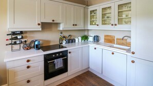 A modern kitchen with white cabinetry, a built-in oven, a sink, and a wine rack.
