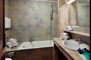 Bathroom features a large bathtub, sink, and shower area with a geometric tile pattern.
