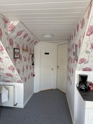 A hallway with a white door marked 'PRIVATE,' a radiator, a coffee maker, and a framed butterfly picture on the wall. - Aunt Janni's Summer Pension (Bogense)