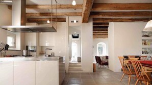 A modern kitchen with white cabinets, a central island, and a dining area with wooden chairs and a red tablecloth. - Casa Leopoldo in Castiglione Chiavarese (Castiglione Chiavarese)