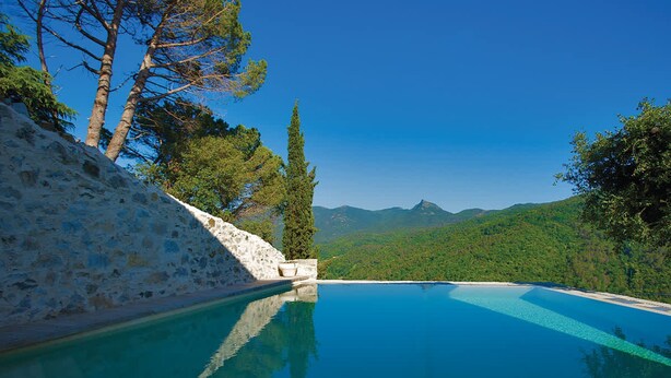 A clear blue pool with a wooden deck, surrounded by stone walls and trees, overlooking a mountainous landscape. - Casa Leopoldo in Castiglione Chiavarese (Castiglione Chiavarese)