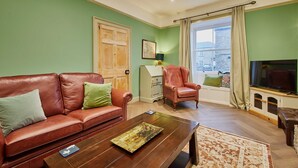 A living room with a brown leather sofa, a wooden coffee table, and a television on a wooden cabinet. - Host Stay Temple Terrace (Richmond)