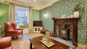 A living room with a fireplace, a sofa, a coffee table, and a window with curtains. - Host Stay Temple Terrace (Richmond)