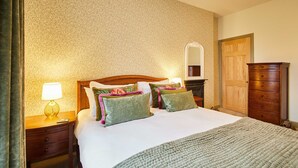 A neatly made bed with a green blanket, a wooden nightstand with a lamp, and a wooden dresser. - Host Stay Temple Terrace (Richmond)