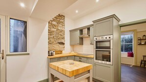 A modern kitchen with a stone accent wall, built-in appliances, and a wooden island. - Host Stay Temple Terrace (Richmond)