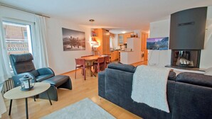 A modern living room with a sofa, a dining table, and a kitchen in the background. - Apartment Lora (Zermatt)