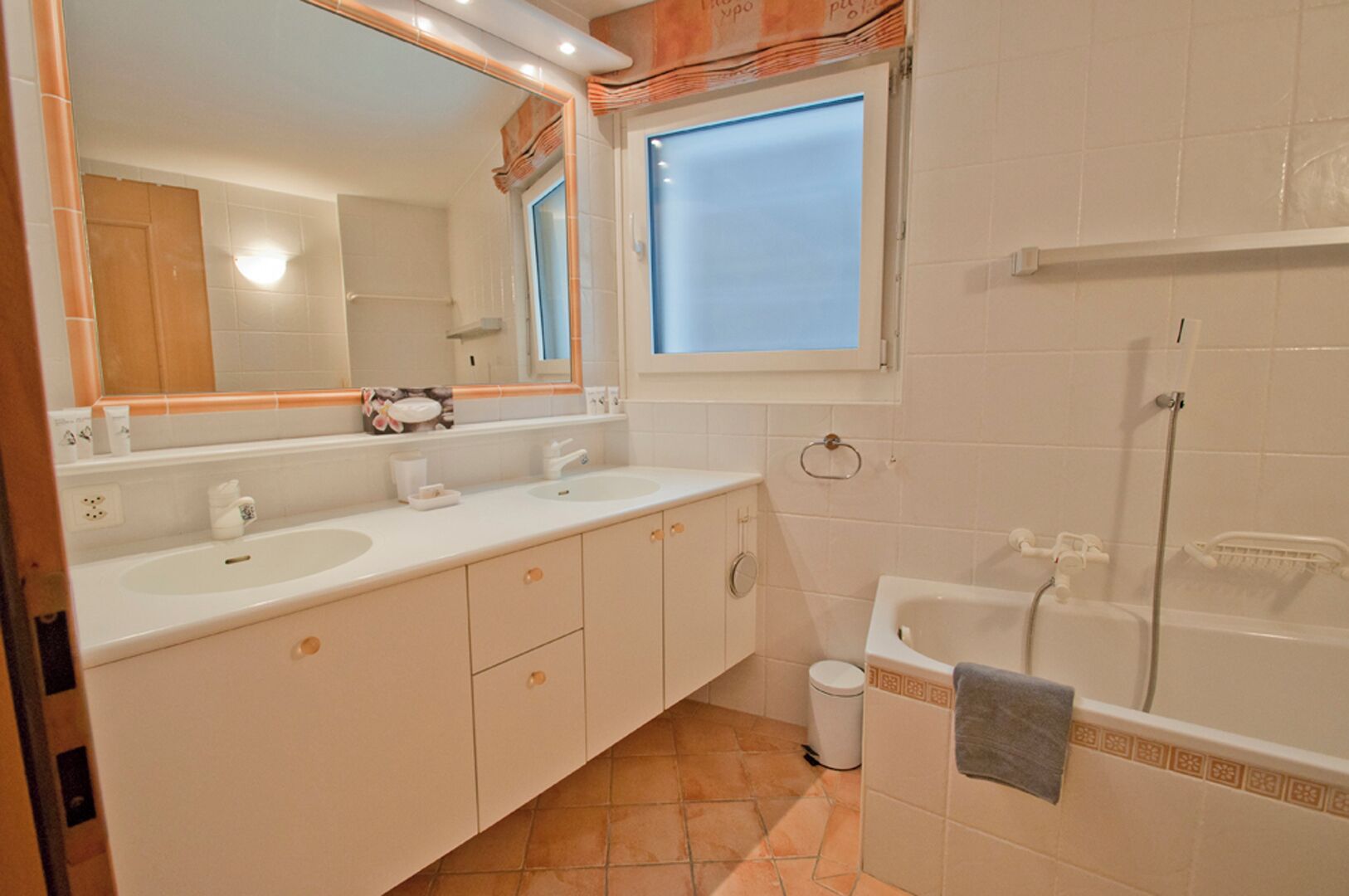 A bathroom with two sinks, a large mirror, a window, a shower, and a towel rack.