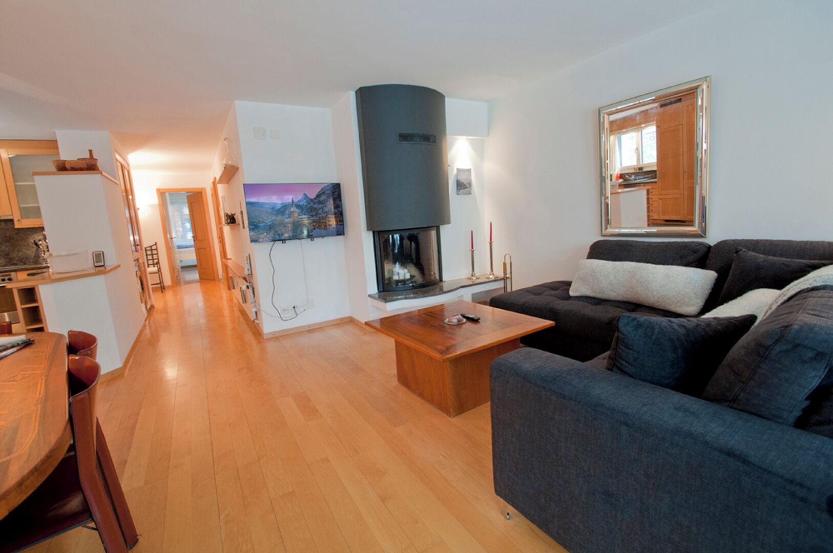 A modern living room with a sofa, a coffee table, a fireplace, and a television.