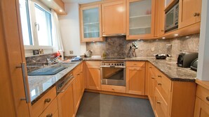 A modern kitchen with wooden cabinets, a built-in oven, and a microwave. - Apartment Lora (Zermatt)