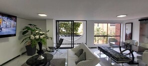 A modern living room with a sofa, a coffee table, a hammock, and a dining area with chairs and a glass table.