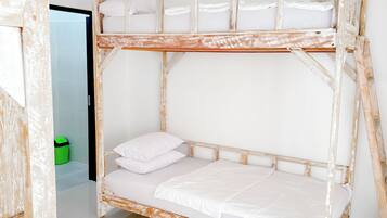Una cama litera con ropa de cama blanca en una habitación con paredes blancas y piso de baldosas.