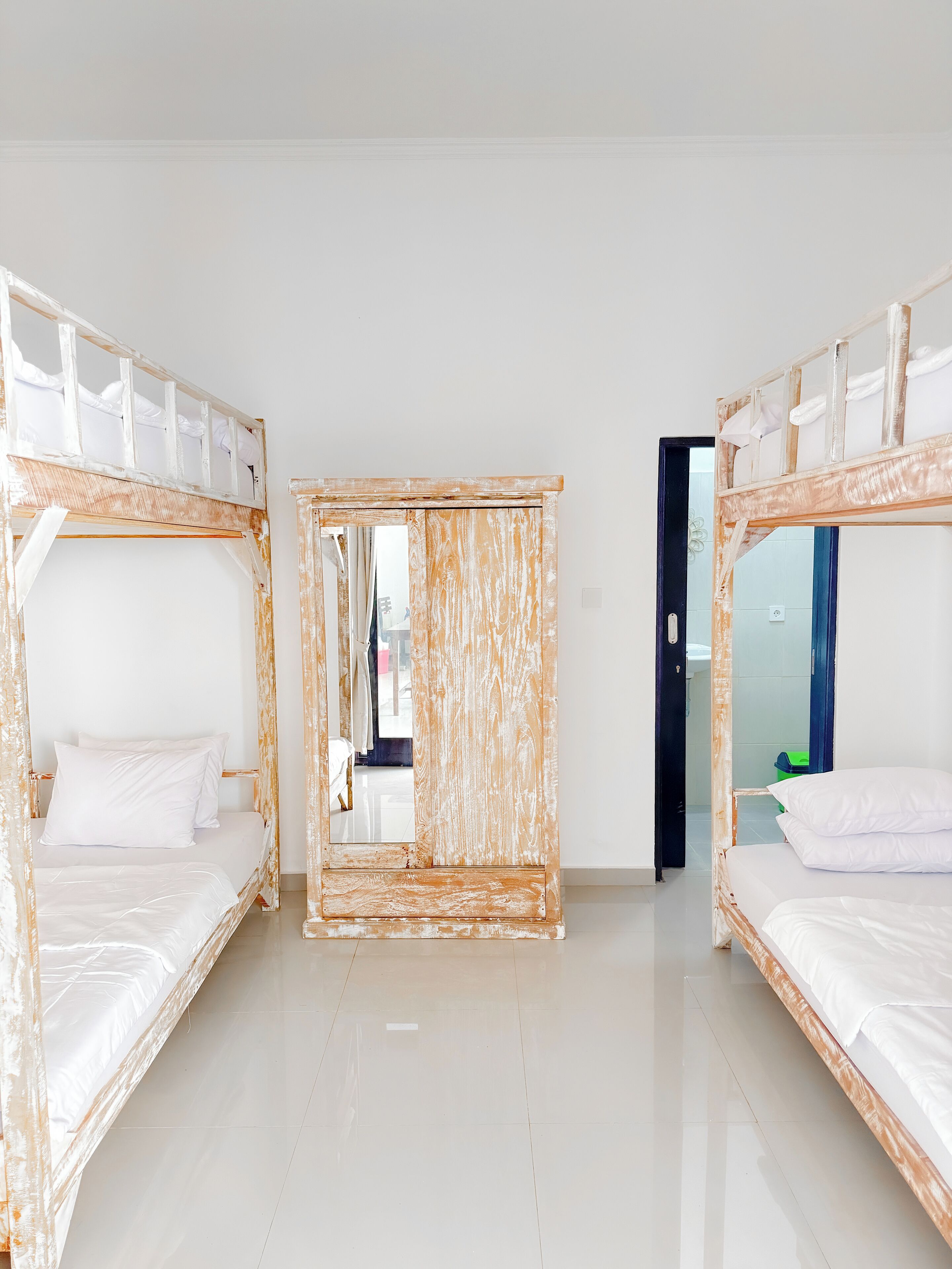 A room with two bunk beds, a large mirror, and a door leading to another room.