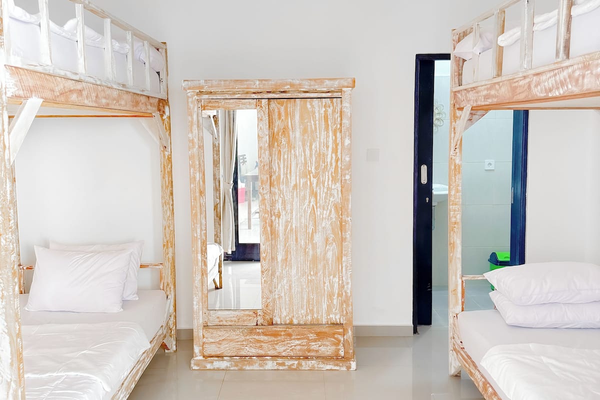 A room with two bunk beds, a large mirror, and a door leading to another room.
