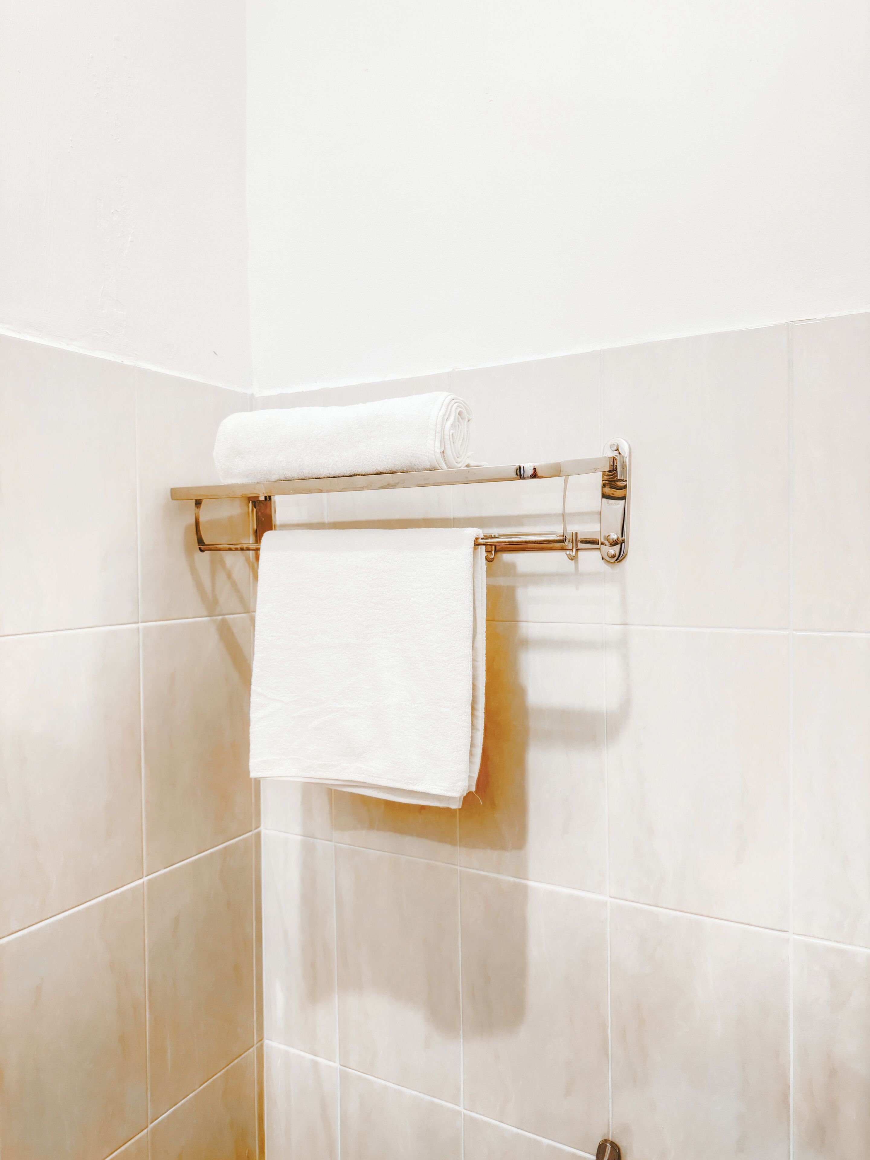 Un baño con un perchero que sostiene dos toallas blancas.