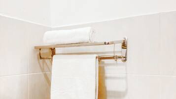 Un baño con un perchero que sostiene dos toallas blancas.