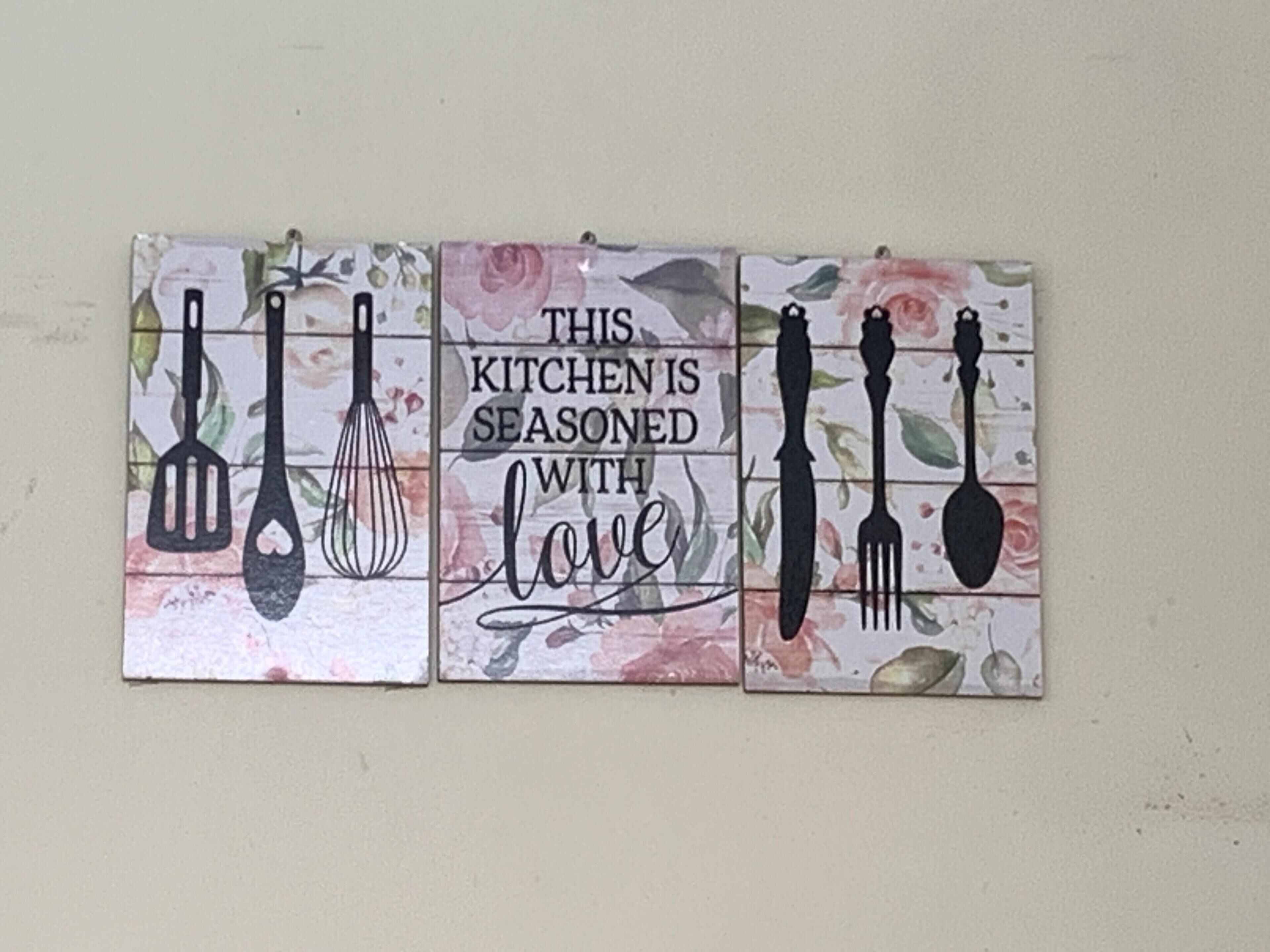Un salpicadero de cocina con un azulejo decorativo que muestra utensilios de cocina y la frase 'This kitchen is seasoned with love'.