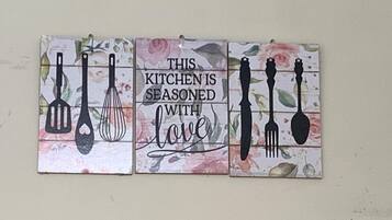 Un salpicadero de cocina con un azulejo decorativo que muestra utensilios de cocina y la frase 'This kitchen is seasoned with love'.