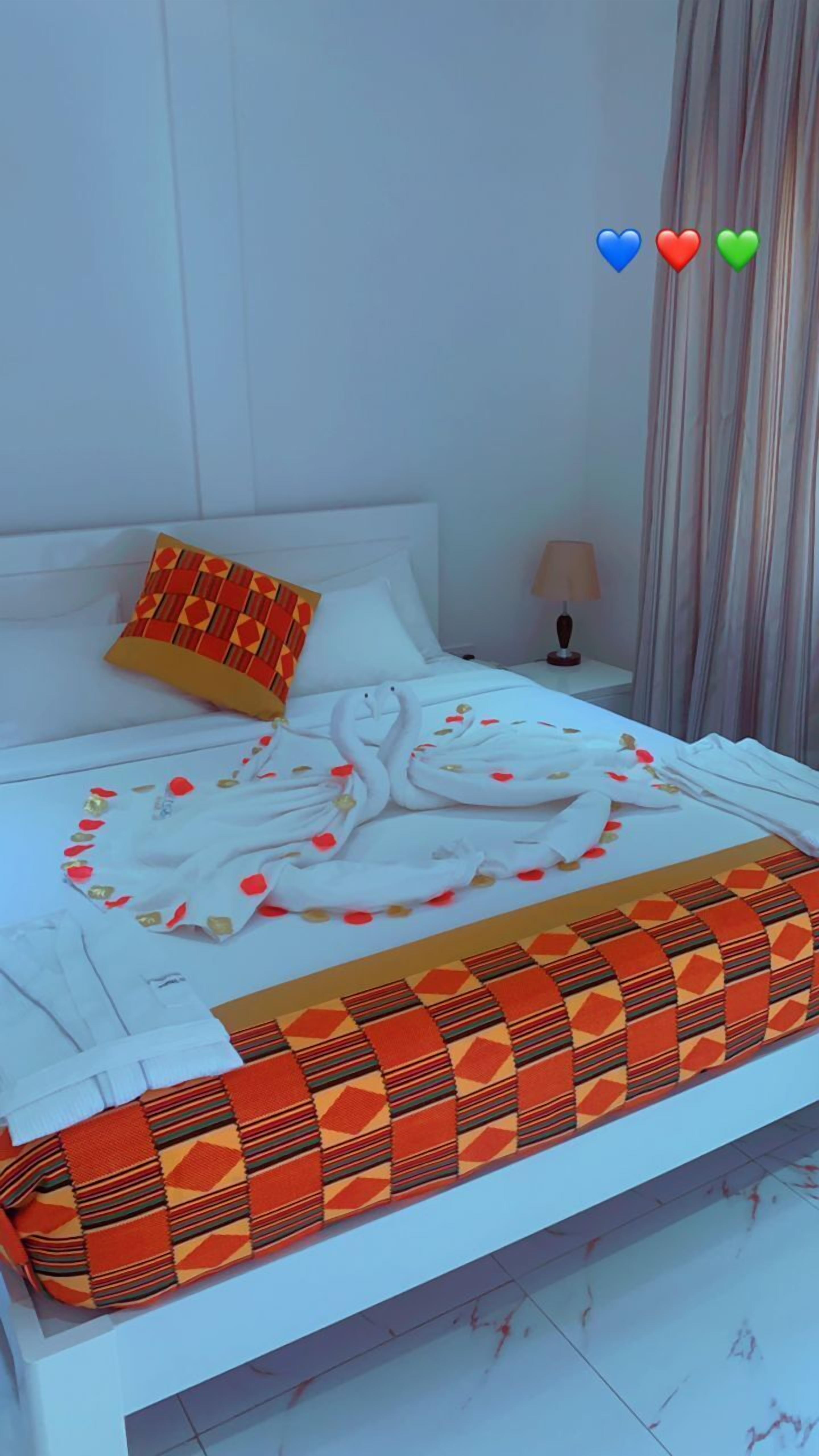 A neatly made bed with a white duvet, a geometric-patterned pillow, and a swan-shaped towel arrangement.