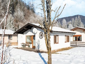 Un edificio cubierto de nieve con una puerta de madera, una ventana y una antena parabólica.