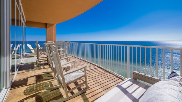 A balcony with a view of the ocean, furnished with chairs and a table. - Phoenix Orange Beach 1906 4 Bedroom Condo (Orange Beach)