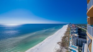 An aerial view of a beach with clear blue waters and a sandy shore. - Phoenix Orange Beach 1906 4 Bedroom Condo (Orange Beach)