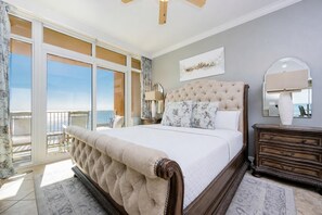 A bedroom with a large bed, a dresser, a nightstand, a window with a view, and a ceiling fan. - Phoenix Orange Beach 1906 4 Bedroom Condo (Orange Beach)