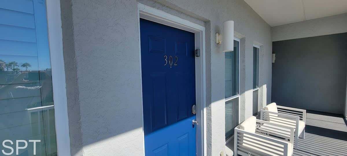 A blue door with the number 302, a white wall, and a balcony with white railings.
