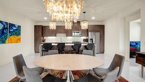A modern kitchen with dark wood cabinets, a central island, and a chandelier.