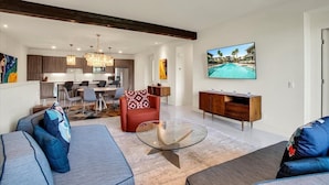 A modern living room with a glass coffee table, a red sofa, and a TV displaying a pool view.