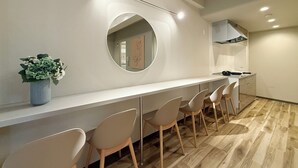 Et moderne køkken med en lang bordplade, et rundt spejl og en potteplante.