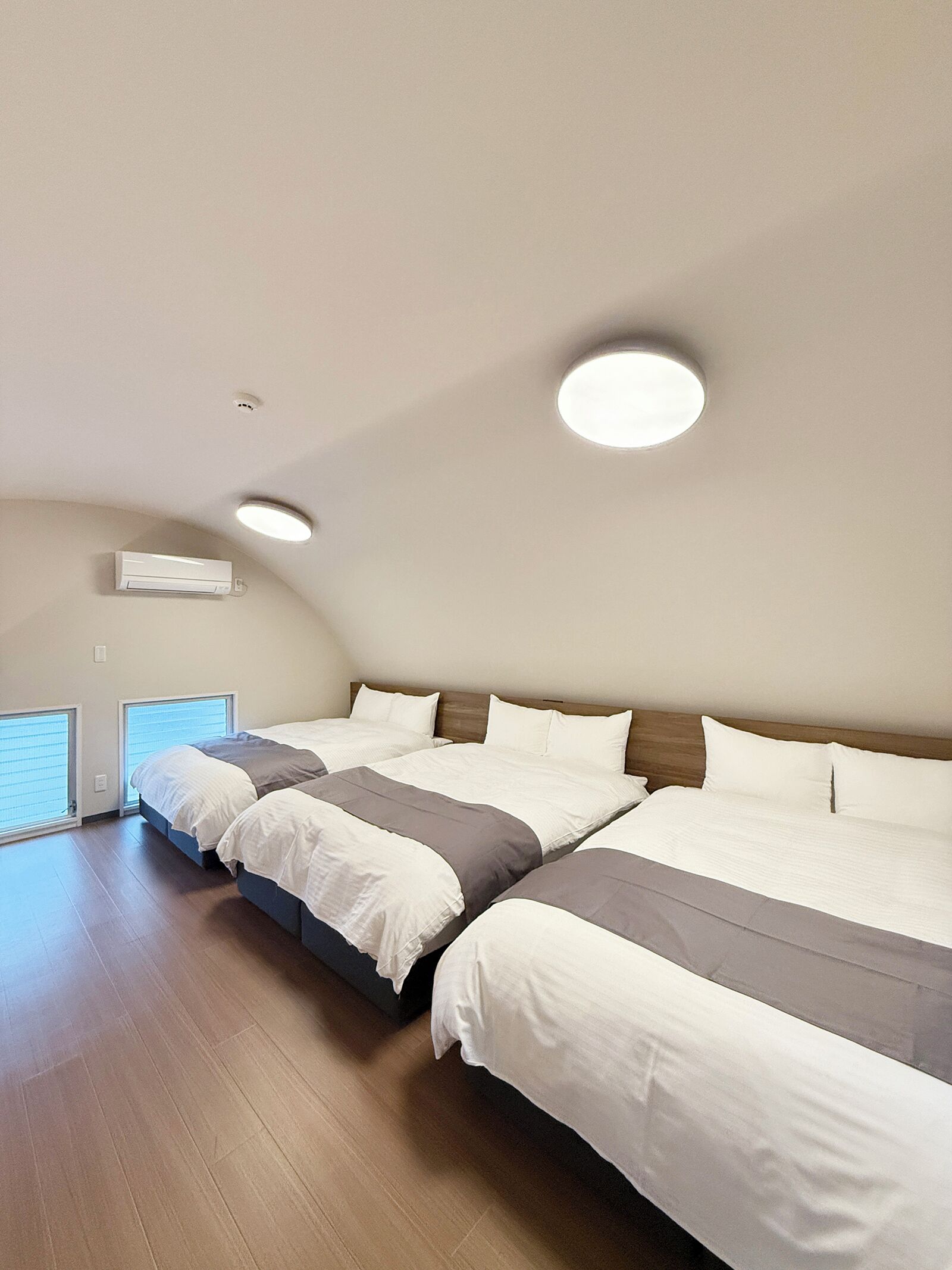 A bedroom with two beds, a ceiling fan, and a window with blinds.