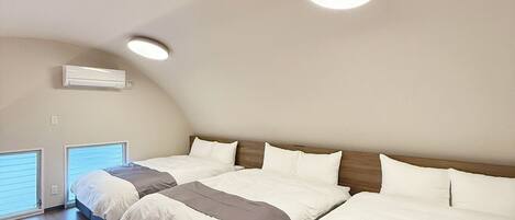 A bedroom with two beds, a ceiling fan, and a window with blinds.