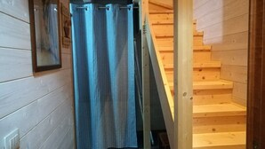 Una estrecha escalera de madera que conduce a una habitación con una cortina a rayas.