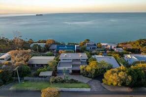 Ein Küstenwohngebiet mit Häusern, einem Schild für 'Peninsula Escapes' und Blick aufs Meer.