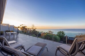 A terrace with a table and chairs, overlooking a scenic ocean view.