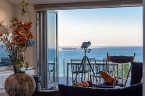 A balcony with a telescope, a chair, and a vase with flowers.