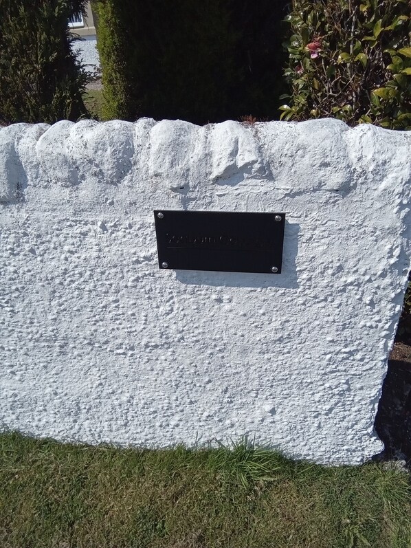A sign on a textured white wall with a metal plate. - Small Detached Cottage in Lamlash.Sleeps 2 (Lamlash)