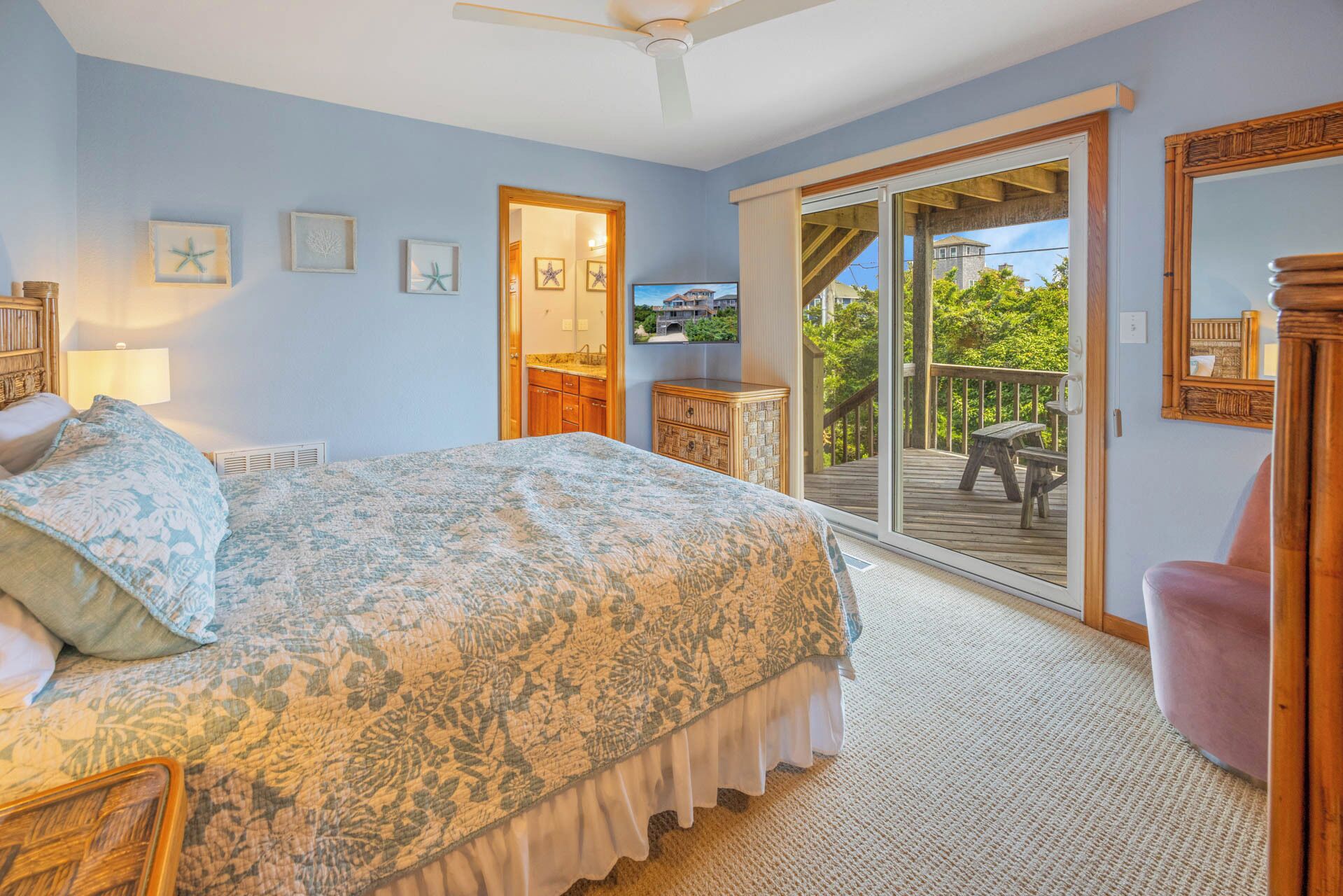 A bedroom with a bed, a dresser, a mirror, and a sliding glass door leading to an outdoor deck.