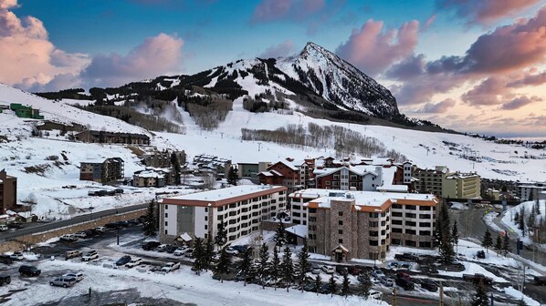 A snow-covered mountain town with multi-story buildings, a ski slope, and a clear sky.