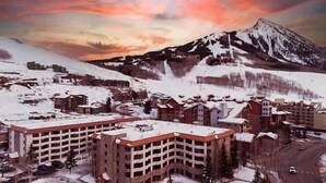 A snow-covered town with buildings and a mountain in the background. - Grand Lodge 412 & 414 — Pets OK | Hot Tub | Pool | Sleeps 8 (Crested Butte)