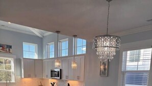 Una cocina amplia con armarios blancos, una isla central e iluminación colgante.